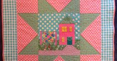 a quilted wall hanging with a house on it's side and polka dots around the edges