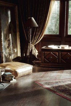 a living room filled with furniture and a large window next to a table covered in books