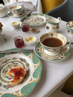 a table topped with plates filled with food and cups full of tea next to each other