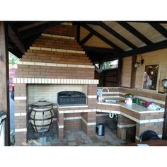 an outdoor kitchen with a brick fireplace and grill