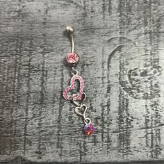 a pink and purple heart belly ring on a wooden surface with the word love written in it