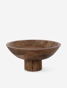 a wooden bowl sitting on top of a white surface with no one around it,