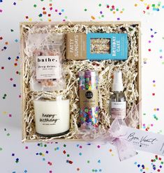 an open gift box with confetti, candles, and other items in it