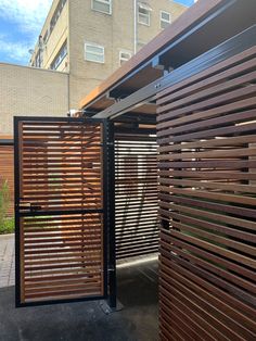 an open wooden gate on the side of a building next to a tall brick building