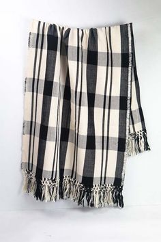 a black and white checkered blanket hanging on a wall with tassels around the edges