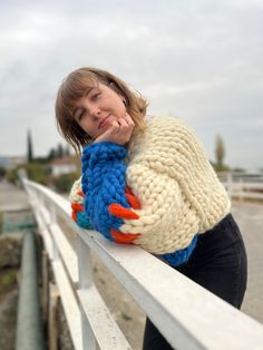 a woman leaning on a fence with her hand under her chin