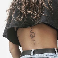 a woman's back with a tattoo on her left side and a snake in the middle