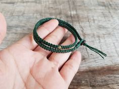 a person holding two green bracelets in their hand on top of a wooden table