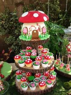 a table topped with cupcakes covered in green frosting and mushroom shaped decorations