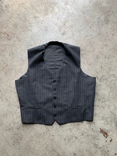 Vintage Dark Gray Waistcoat Vest Gilet in great vintage condition without stains or holes. Size: N/A please check the measurements to be sure, it runs smaller measurements: - Chest(armpit to armpit: 55m(21.6") - Length from the backside(Center bottom of the collar to center bottom of the garment): 52cm(20.4") - Shoulder to shoulder: 38cm(14.9") NOTE: Due to the age, clothing/items can shrink or it may be that the sizing from that time the item was made in, is not the same as the sizing in modern Vintage Workwear Vest Outerwear, Retro Sleeveless Outerwear For Work, Vintage Fitted Sleeveless Outerwear, Fitted Sleeveless Vintage Outerwear, Tailored Vintage Winter Vest, Tailored Vintage Fall Vest, Vintage Winter Vest Outerwear, Retro Fitted Sleeveless Outerwear, Vintage Workwear Vest