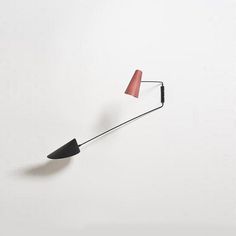 a red and black wall lamp on a white wall next to a light bulb that is attached to the wall