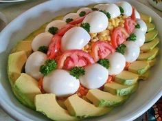 a white bowl filled with sliced up vegetables and hard boiled eggs on top of avocado