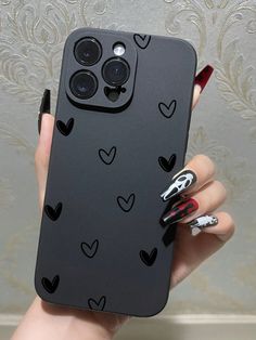 a woman's hand holding a black phone case with hearts on it