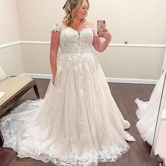 a woman in a wedding dress taking a selfie with her cell phone while looking at herself in the mirror