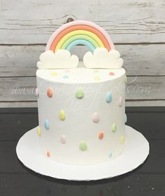 a white cake decorated with rainbows and clouds