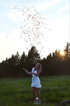 a woman in a white dress holding a tennis racquet while confetti falls from the sky