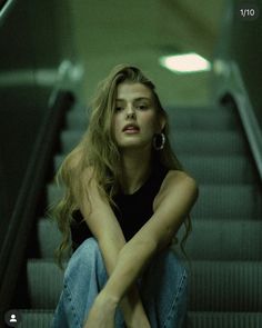 a woman sitting on an escalator with her legs crossed in front of her