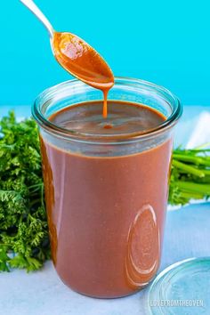 a spoon full of sauce sitting on top of a table next to some parsley