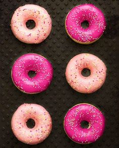 four donuts with pink frosting and sprinkles arranged in a grid