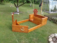 a wooden bed frame sitting on top of a lush green field next to a tree