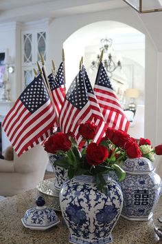 red roses in a blue and white vase with american flags sticking out of the top