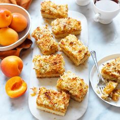 several pieces of cake sitting on a plate next to bowls of fruit and a cup of coffee