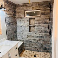 a walk in shower sitting next to a white sink under a window on top of a wooden wall