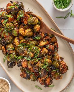 a white plate topped with brussel sprouts next to a wooden spoon