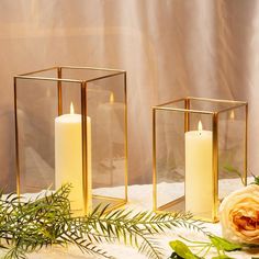 three candles are sitting next to each other on a table with flowers and greenery