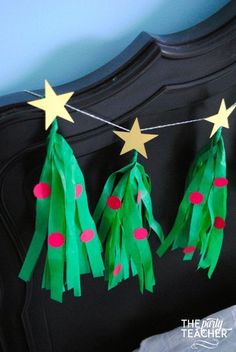 three paper christmas trees hanging from a string on a bed with stars and polka dots