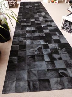 a black and white area rug on the floor in a living room with potted plants