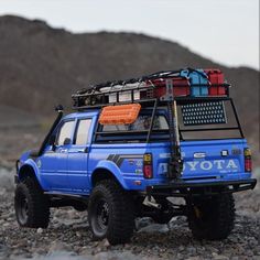 a blue pick up truck with luggage strapped to it's back in the desert