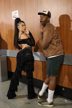 a man and woman standing next to each other in front of a wooden paneled wall