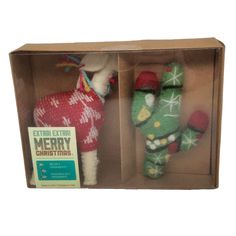 two stuffed animals are in a box with christmas sweaters and mittens on them