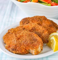 two chicken patties on a white plate with a side salad