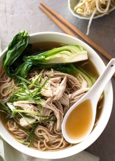 a bowl filled with noodles, meat and greens