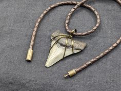 #ST639 1 13/16 inch fossil megalodon shark tooth pendant double wrapped with antique bronze wire. The pendant is strung an antique brown braided leather cord with a matching bayonet-style clasp. The cord can be cut to a length of 14, 16, 18, 20, 22, 24, 26, or 28 inches depending on your preference. This tooth was found in coastal South Carolina. PLEASE NOTE: If you're not sure how long to make your necklace cord, I suggest that you find and measure your preferred length with a piece of string (for reference, a 14 inch cord would be a choker on a slender woman). Antique Adjustable Brown Jewelry, Adjustable Antique Brown Jewelry, Adjustable Brown Jewelry For Collectors, Coastal South Carolina, Shark Tooth Pendant, Tooth Pendant, Megalodon Shark, Necklace Cord, Shark Tooth