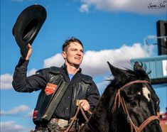 a man riding on the back of a black horse with a hat in his hand