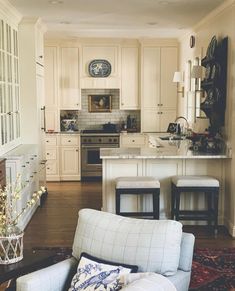 a living room filled with furniture and a kitchen in the back drop off wall behind it