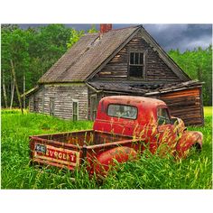 an old red truck sitting in the middle of a field next to a wooden house