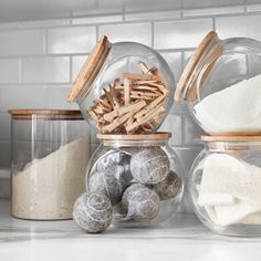 three glass jars filled with different types of items on top of a white countertop