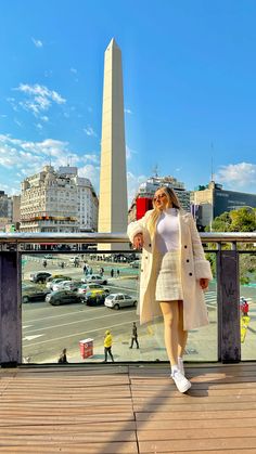 a woman is standing on a bridge in front of the washington monument