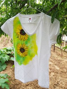 a t - shirt with sunflowers painted on it hanging from a tree