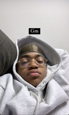 a young man wearing glasses and a hoodie with the word gm above his head