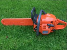 an orange chainsaw is laying on the grass