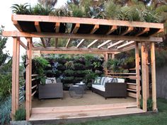 an outdoor living area with couches, potted plants and wooden pergoline