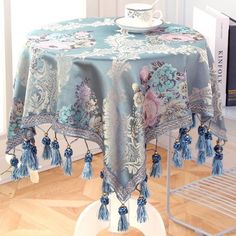 a blue table cloth with tassels on it in front of a book shelf