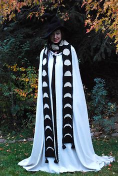 a woman dressed up in a white and black costume with a long cloak over her shoulders