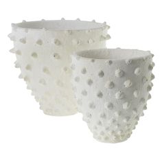 two white vases sitting side by side on a white surface with holes in them