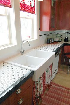 a kitchen with red cabinets and white counter tops